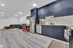 Kitchen with modern cabinets, stainless steel appliances, open floor plan, light wood finished floors, and recessed lighting - 