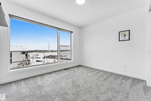 Empty room featuring light carpet and baseboards - 77 5 Rondeau Drive, St. Albert, AB - Indoor Photo Showing Other Room