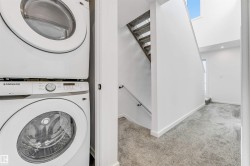 Laundry area with stacked washer and clothes dryer and carpet floors - 