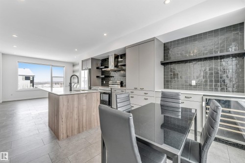 Two tone kitchen with open shelves, a center island with sink, dual tone cabinetry, stainless steel appliances, and wine cooler - 77 5 Rondeau Drive, St. Albert, AB - Indoor Photo Showing Kitchen With Upgraded Kitchen