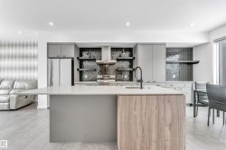 Kitchen with open shelves, two tone cabinets, a center island with sink, stainless steel appliances, and exhaust hood - 