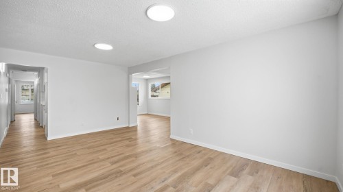 Family room with a textured ceiling and light wood-type flooring - 3419 143 Avenue Nw, Edmonton, AB - Indoor Photo Showing Other Room