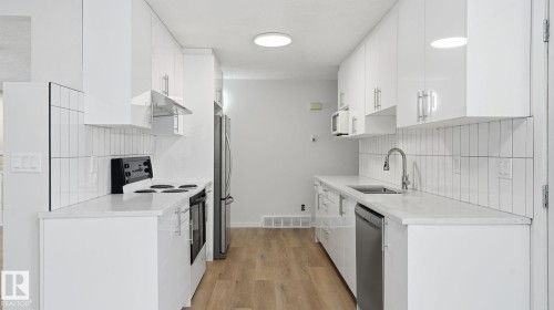 Kitchen featuring stainless steel appliances, light stone countertops, light wood-style flooring, white cabinets, and backsplash - 3419 143 Avenue Nw, Edmonton, AB - Indoor Photo Showing Kitchen