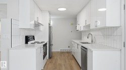 Kitchen featuring stainless steel appliances, light stone countertops, light wood-style flooring, white cabinets, and backsplash - 