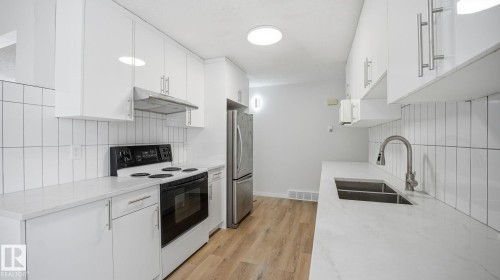 Kitchen featuring range with electric stovetop, light stone counters, and white cabinetry - 3419 143 Avenue Nw, Edmonton, AB - Indoor Photo Showing Kitchen With Double Sink