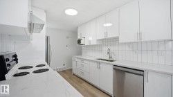 Kitchen featuring stainless steel appliances, white cabinets, and light stone counters - 