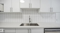 Kitchen with light stone counters, white cabinets, and dishwasher - 