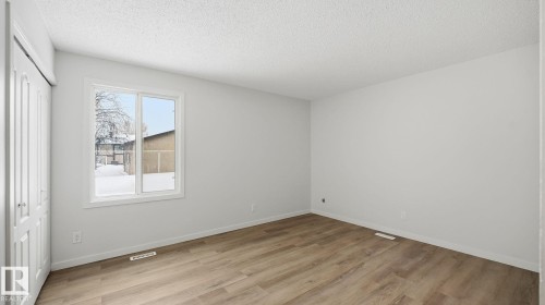 Unfurnished bedroom featuring a closet, light wood finished floors, and a textured ceiling - 3419 143 Avenue Nw, Edmonton, AB - Indoor Photo Showing Other Room