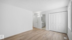 Unfurnished bedroom featuring a closet, light wood-type flooring, a textured ceiling, and ensuite bath - 