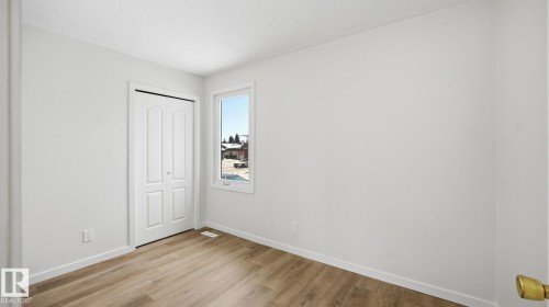Unfurnished bedroom featuring light wood-type flooring, a closet, and a textured ceiling - 3419 143 Avenue Nw, Edmonton, AB - Indoor Photo Showing Other Room