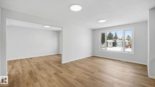 Family room with a textured ceiling and light wood finished floors - 3419 143 Avenue Nw, Edmonton, AB - Indoor Photo Showing Other Room