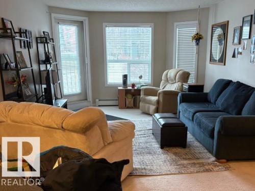 Living room featuring baseboard heating and carpet - 118 396 Silverberry Road Nw, Edmonton, AB - Indoor Photo Showing Living Room