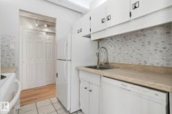 Kitchen featuring white appliances, light countertops, white cabinets, tasteful backsplash, and light tile patterned floors - 