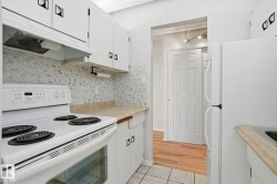 Kitchen featuring white appliances, light countertops, white cabinets, and decorative backsplash - 