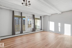 Empty room with a baseboard radiator, beam ceiling, a textured ceiling, light wood-style flooring, and hanging lights - 