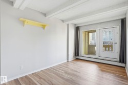 Unfurnished room with light wood finished floors, a textured ceiling, baseboard heating, and beamed ceiling - 