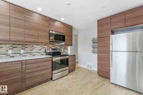 Kitchen with stainless steel appliances, light stone counters, recessed lighting, modern cabinets, and tasteful backsplash - 13911 117 Avenue, Edmonton, AB - Indoor Photo Showing Kitchen With Stainless Steel Kitchen With Upgraded Kitchen