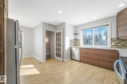 Kitchen featuring wood finish cabinetry, stainless steel appliances, light stone counters, modern cabinets, and backsplash - 