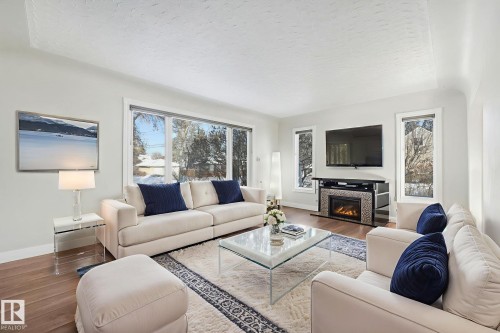 Living room with wood finished floors, a glass covered fireplace, and a textured ceiling - 13911 117 Avenue, Edmonton, AB - Indoor Photo Showing Living Room With Fireplace