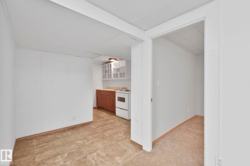 Two tone kitchen with glass insert cabinets, light countertops, white range with electric cooktop, and two tone cabinetry - 13911 117 Avenue, Edmonton, AB - Indoor