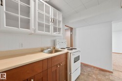 Kitchen featuring white electric stove, light countertops, glass insert cabinets, and wood finish cabinets - 
