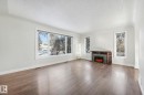 Unfurnished living room featuring a textured ceiling, a fireplace, and wood finished floors - 13911 117 Avenue, Edmonton, AB  - Indoor Photo Showing Living Room With Fireplace 