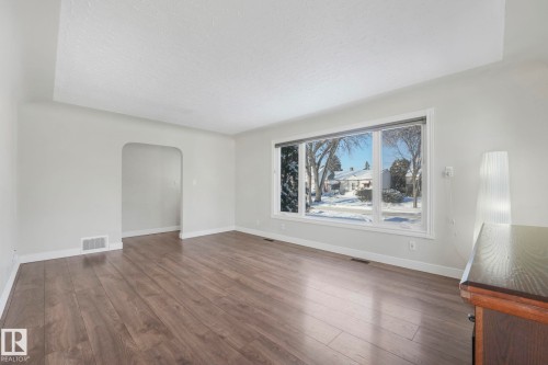 Spare room featuring arched walkways, a textured ceiling, and dark wood-style floors - 13911 117 Avenue, Edmonton, AB - Indoor Photo Showing Other Room