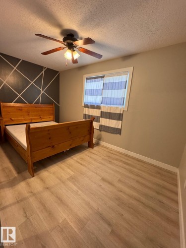 Room featuring wood-finish flooring, a contemporary ceiling fan with integrated lighting, and a window with horizontal striped coverings - 2910 132A Avenue, Edmonton, AB - Indoor
