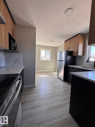 Modern kitchen with light wood-finish upper cabinetry and dark lower cabinetry - 2910 132A Avenue, Edmonton, AB - Indoor Photo Showing Kitchen