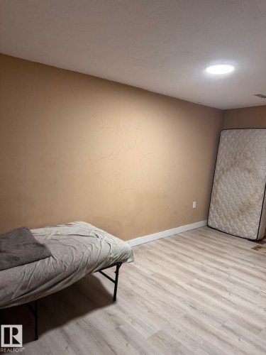 Light wood-finish flooring with white baseboards and neutral wall tones - 2910 132A Avenue, Edmonton, AB - Indoor Photo Showing Bedroom