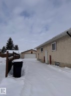 View of snowy exterior with stucco siding, an outbuilding, and a detached garage - 