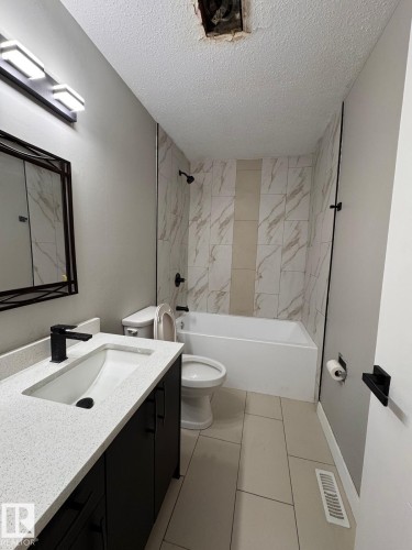 Modern bathroom featuring a single vanity with stone-finish countertop, undermount sink, and matte black faucet - 2910 132A Avenue, Edmonton, AB - Indoor Photo Showing Bathroom
