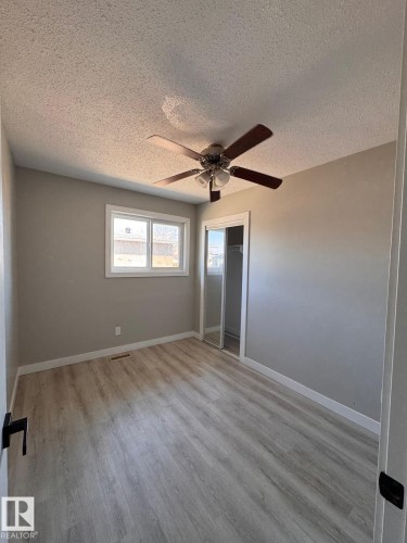 Spacious room featuring wood-finish flooring, neutral paint palette, and a ceiling fan with integrated lighting - 2910 132A Avenue, Edmonton, AB - Indoor Photo Showing Other Room