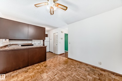 Kitchen with dark wood finish cabinets, white appliances, parquet floors, a textured ceiling, and ceiling fan - 11922 138 Avenue, Edmonton, AB - Indoor Photo Showing Kitchen
