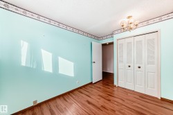 Unfurnished bedroom with a closet, wood finished floors, a textured ceiling, and a chandelier - 