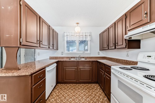 Kitchen featuring white appliances, a textured ceiling, light stone countertops, and light flooring - 11922 138 Avenue, Edmonton, AB - Indoor Photo Showing Kitchen With Double Sink