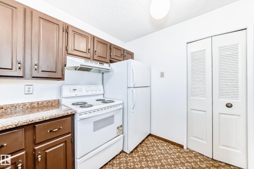 Kitchen featuring white appliances, light flooring, and a textured ceiling - 11922 138 Avenue, Edmonton, AB - Indoor Photo Showing Kitchen