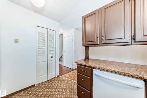 Kitchen featuring white dishwasher, a textured ceiling, and light stone countertops - 11922 138 Avenue, Edmonton, AB - Indoor Photo Showing Other Room