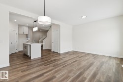 Kitchen featuring pendant lighting, open floor plan, a kitchen island with sink, and dark wood-style flooring - 