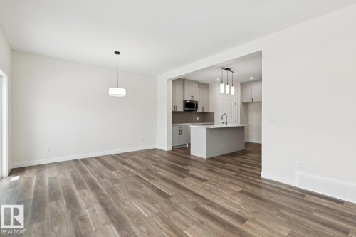 Kitchen with light countertops, a kitchen island with sink, open floor plan, hanging light fixtures, and dark wood-type flooring - 407 26 Street, Edmonton, AB - Indoor Photo Showing Kitchen