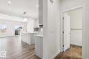 Kitchen featuring backsplash, dark wood-style floors, decorative light fixtures, a center island with sink, and white cabinetry - 407 26 Street, Edmonton, AB  - Indoor Photo Showing Kitchen 