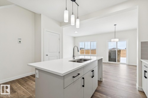 Kitchen featuring white cabinets, pendant lighting, and dark wood finished floors - 407 26 Street, Edmonton, AB - Indoor Photo Showing Kitchen With Double Sink