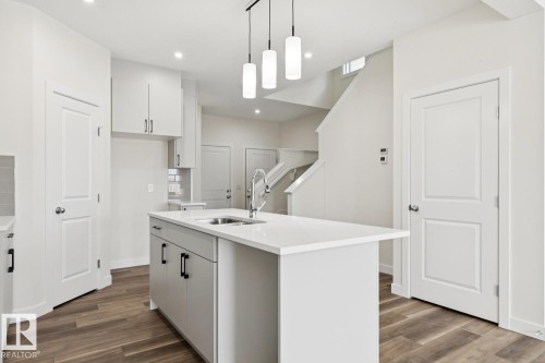 Kitchen with white cabinetry, hanging light fixtures, a kitchen island with sink, and dark wood finished floors - 407 26 Street, Edmonton, AB - Indoor Photo Showing Kitchen