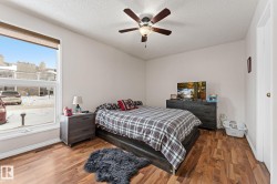 Bedroom with wood finished floors, a ceiling fan, and a textured ceiling - 