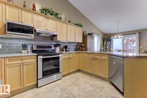 Kitchen featuring stainless steel appliances, light wood finish cabinets, a peninsula, and a chandelier - 20148 46 Avenue, Edmonton, AB - Indoor Photo Showing Kitchen