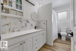 Full bath featuring vanity, a shower with shower curtain, light wood-style floors, decorative backsplash, and tile walls - 