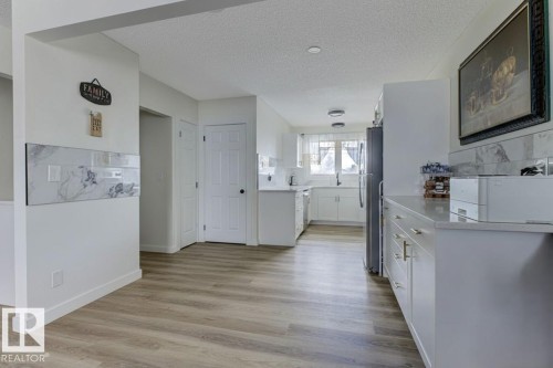 Kitchen with a textured ceiling, white cabinets, light wood-type flooring, and freestanding refrigerator - 13211 71 Street, Edmonton, AB - Indoor