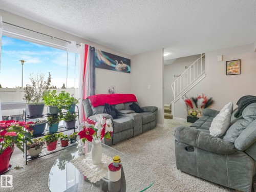 Carpeted living room featuring stairway and a textured ceiling - 13271 47 Street, Edmonton, AB - Indoor Photo Showing Living Room
