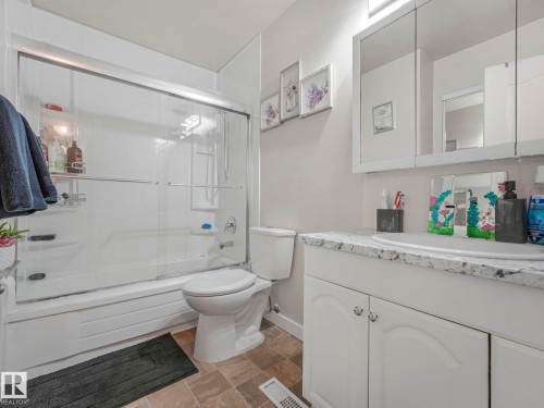 Full bath featuring vanity, combined bath / shower with glass door, and stone finish flooring - 13271 47 Street, Edmonton, AB - Indoor Photo Showing Bathroom