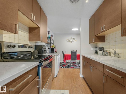 Kitchen with stainless steel range with electric cooktop, tasteful backsplash, light wood-style flooring, light countertops, and a textured ceiling - 13271 47 Street, Edmonton, AB - Indoor Photo Showing Kitchen